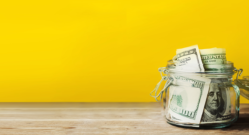 cash-in-jar-on-counter-yellow-background